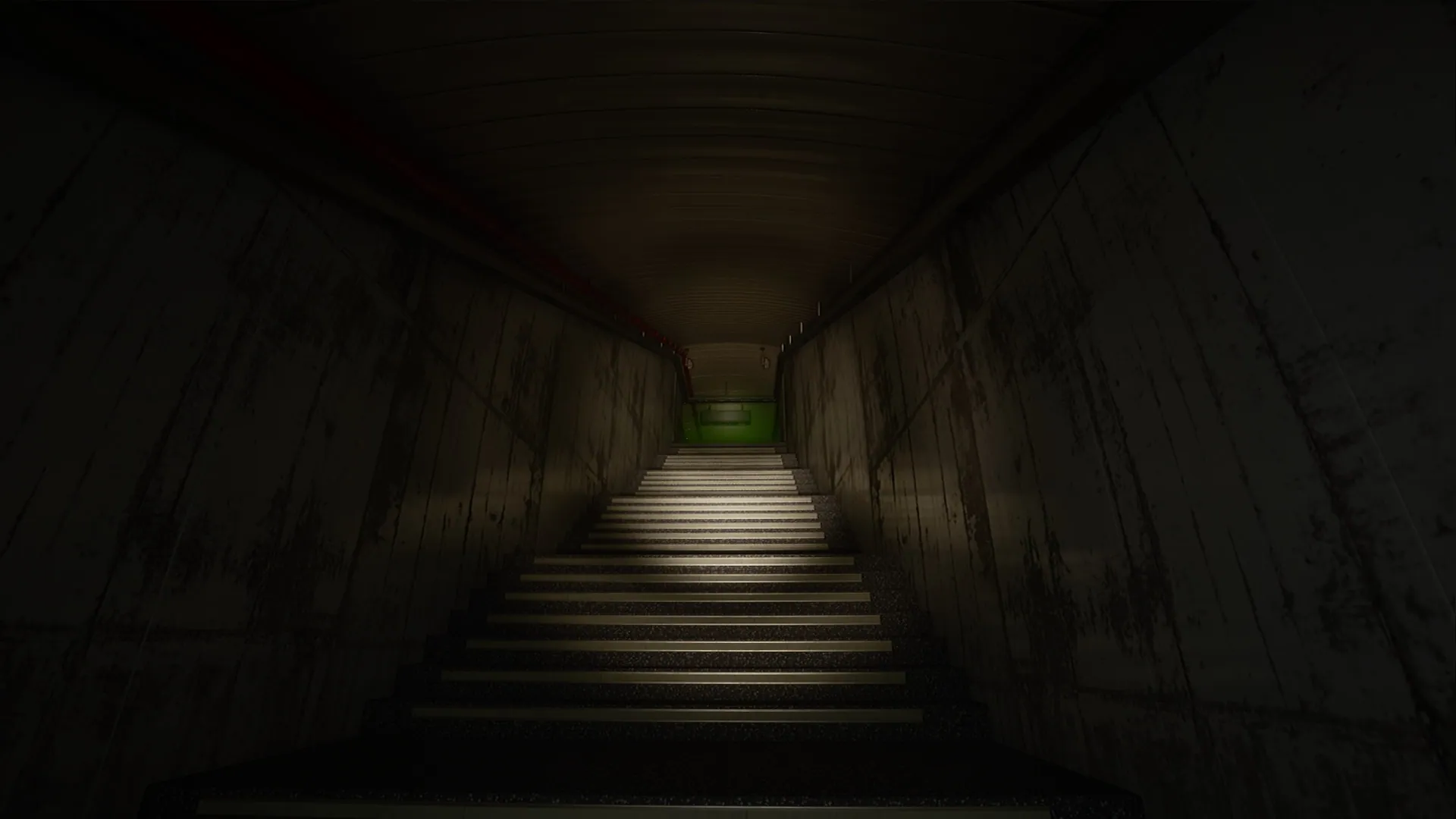 Long corridor with stairs leading down to a green exit sign